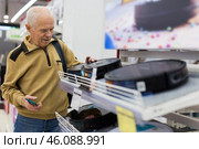 Senor man pensioner buying Robotic vacuum cleaner in showroom of electrical appliance store. Стоковое фото, фотограф Татьяна Яцевич / Фотобанк Лори