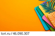 Tropical-design notebooks pop against a vibrant orange backdrop, inspiring creativity. Стоковое AI-изображение, AI-художник Елена Старчак / Фотобанк Лори