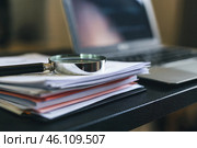 Magnifying glass lies on a stack of business papers. Стоковое AI-изображение, AI-художник Дмитрий Киселёв / Фотобанк Лори