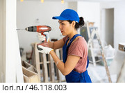 Woman builder using drill to bore hole in wall. Стоковое фото, фотограф Яков Филимонов / Фотобанк Лори