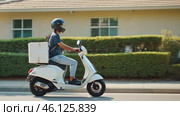 Delivery driver riding scooter on suburban street. Стоковое AI-видео, аниматор Юрий Поздников / Фотобанк Лори
