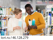During shopping, African male customer with European wife advised and choose shampoo or shower gel. Стоковое фото, фотограф Яков Филимонов / Фотобанк Лори