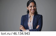 Confident Businesswoman Smiling with Folded Arms on Gray Background. Стоковое видео, видеограф Данил Руденко / Фотобанк Лори