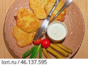 Hash browns. Hash brown potato with white sauce on modern ceramic plate on wood Table in a Cafe or Restaurant. Traditional pancakes boxty raggmunk. Potatoes pancakes latkes, flapjacks, or potato vada. Стоковое фото, фотограф Марина Демидюк / Фотобанк Лори