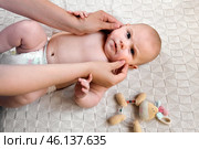 Mother Massaging and Lubricates Baby Face Gently. Mom Applying Cream or Oil on Her Child's Face. Happy Newborn Baby Smiling. Neonate Toddler at Cozy Home Space. Skin Care, Baby Development Concept. Стоковое фото, фотограф Марина Демидюк / Фотобанк Лори