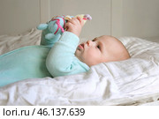 Cute Newborn Baby Lying on the Back and Plays with Colorful Toys. Little Three Month Child Takes a Toy. Portrait of Playful Neonate Toddler. Concept of Childhood, New Life, Baby Care. Top View. Стоковое фото, фотограф Марина Демидюк / Фотобанк Лори