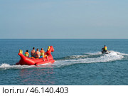 A group of tourists riding on the sea on an inflatable structure towed by an aquabike. Summer, vacation, recreation. Copy space. Стоковое фото, фотограф Роман Дзюбало / Фотобанк Лори