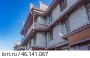 Chinese architecture. A fragment of a brick apartment building. Windows on the facade, balconies with railings, roofs with curved cornices. The blue sky. China. Fenghuang. Стоковое фото, фотограф Вера Ивановна Кубарева / Фотобанк Лори