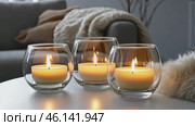 Candles and Soft Textile. Cozy Living Room Details. Flickering burning candle glasses, plush knit blanket. Atmosphere of serenity and comfort. Gray and brown color scheme. Modern boho house interior. Стоковое AI-видео, аниматор Марина Демидюк / Фотобанк Лори