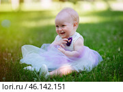 Cute little baby girl sitting on the grass in the Park on a warm summer day. Walking and playing in the fresh air. Стоковое фото, фотограф Иван Карпов / Фотобанк Лори
