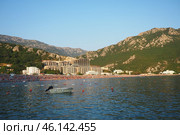 Canj, Montenegro 07.20.2024 Boats and a shore with vacationers, sunbathers and swimmers. Hotels, sun umbrellas, Adriatic waves, buoys. Beach tourism. Vacation travel. Summer day. Pebble rock beach. Редакционное фото, фотограф Юлия Петровская / Фотобанк Лори