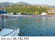 Canj, Montenegro 07.20.2024 Boats and a shore with vacationers, sunbathers and swimmers. Hotels, sun umbrellas, Adriatic waves, buoys. Beach tourism. Vacation travel. Summer day. Pebble rock beach. Редакционное фото, фотограф Юлия Петровская / Фотобанк Лори