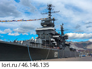 The cruiser "Mikhail Kutuzov", which is a museum ship in the city of Novorossiysk. This Project 68-bis warship was part of the USSR Navy for a long time, and then was turned into a museum, becoming one of the main attractions of the city.The side of the ship with the number "105", which indicates its affiliation with the Navy.You can see the flag garland - a ship decoration used during celebrations.Antennas and radar installations on the masts of the cruiser.A group of tourists on board, inspecting the ship.Mooring ropes secured to the pier.The protective paint of the hull is a characteristic dark gray color. (2023 год). Редакционное фото, фотограф Анна Кривицкая / Фотобанк Лори