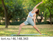 Woman practicing yoga in garden, performing Anjaneyasana, or Crescent Moon Pose. Стоковое фото, фотограф Яков Филимонов / Фотобанк Лори
