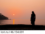 Against the background of an orange sea sunset, there is a silhouette of a girl bowing her head, Стоковое фото, фотограф Коханова Наталья / Фотобанк Лори