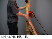 Technician operating hand winch with wooden structure. Стоковое фото, фотограф Юрий Поздников / Фотобанк Лори