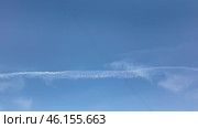 Contrails creating patterns in the clear blue sky above a tranquil landscape during midday. Timelapse. Стоковое видео, видеограф Наталия Попова / Фотобанк Лори