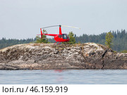 Частный вертолёт Robinson R44 приземлился на скалу дикого острова в Карелии (2022 год). Редакционное фото, фотограф Сергей Крамарев / Фотобанк Лори