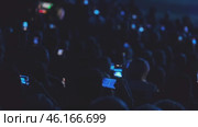 Audience members recording an event using smartphones in a dimly lit venue. Стоковое видео, видеограф Антон Гвоздиков / Фотобанк Лори