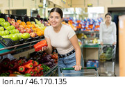 Female buyer selects ripe bell peppers in the vegetable section of supermarket. Стоковое фото, фотограф Яков Филимонов / Фотобанк Лори