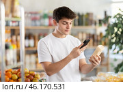 Male buyer checks suitability - scans QR code on jar of mayonnaise label in grocery store. Стоковое фото, фотограф Яков Филимонов / Фотобанк Лори