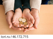 Hands of young man and his son holding coins on wooden table. Concept of child support. Стоковое фото, фотограф Pixel_shot / Фотобанк Лори