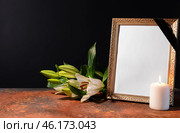 Blank funeral frame, candle and flowers on table against black background. Стоковое фото, фотограф Pixel_shot / Фотобанк Лори