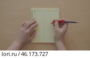 Yellow notepad for and against, reasons to do, postpone. Lined notebook for list of answers on pale background, hands with marker writing comparison. Account of reasons, doubts. Shopping time concept. Стоковое видео, видеограф Елизавета Малкова / Фотобанк Лори