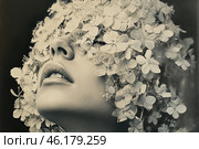 A woman with a face covered in delicate white flowers. Her gaze is directed upwards, her lips are slightly parted. The flowers, as if covering her entire head, create the effect of a veil that hides her eyes and face, giving the image a mysterious and enigmatic quality. The image is made in black and white tones, which enhances the contrast and highlights the textures on the skin and flowers. Стоковое AI-изображение, AI-художник Анна Кривицкая / Фотобанк Лори