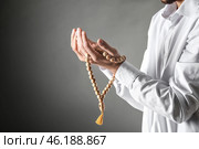 Young Muslim man with rosary beads praying on dark background (2018 год). Стоковое фото, фотограф Pixel_shot / Фотобанк Лори