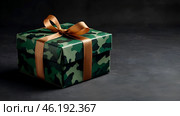 The concept of Defender of the Fatherland Day on February 23. Gift camouflage box with a festive satin ribbon bow on a dark green background. Стоковое AI-изображение, AI-художник Photojuli / Фотобанк Лори