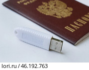 Устройство  USB eToken  (рутокен) белого цвета, устройство для хранения электронной цифровой подписи (ЭЦП) и информации для аутентификации пользователя и паспорт на белом фоне. Редакционное фото, фотограф Snezka / Фотобанк Лори
