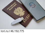 Устройство  USB eToken  (рутокен) белого цвета, устройство для хранения электронной цифровой подписи (ЭЦП) и информации для аутентификации пользователя, паспорт и телефон с приложением Госуслуги на белом фоне. Редакционное фото, фотограф Snezka / Фотобанк Лори