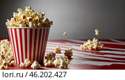 Striped red and white box with salted popcorn. A popular snack at the cinema. Стоковое AI-изображение, AI-художник Photojuli / Фотобанк Лори