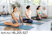 Girl doing stretches in lotus position with side twist in yoga studio. Стоковое фото, фотограф Яков Филимонов / Фотобанк Лори