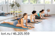 Girl stretching in seated asana Ardha Kapotasana at group yoga session. Стоковое фото, фотограф Яков Филимонов / Фотобанк Лори