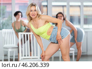 Girl in shorts and tank top stands next to chair, leans on back and performs set of lap dance. Стоковое фото, фотограф Яков Филимонов / Фотобанк Лори