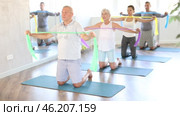 Elderly man kneeling performs exercises with wide elastic band during Pilates workout. Стоковое видео, видеограф Яков Филимонов / Фотобанк Лори