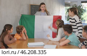 Joyful female teacher discussing with preteens learners state flag of Italy in classroom of middle school. Стоковое видео, видеограф Яков Филимонов / Фотобанк Лори