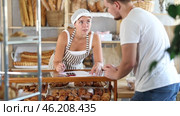In bakery, male visitor and female salesperson work with paper documents and count using phone. Стоковое видео, видеограф Яков Филимонов / Фотобанк Лори
