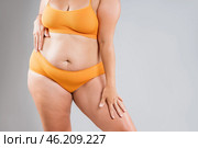 Fat woman in orange underwear on gray background, obesity and cellulite, overweight female body, weight loss concept. Стоковое фото, фотограф Станислав Тарко / Фотобанк Лори