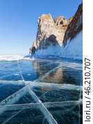 Baikal Lake in sunny cold February day. View of natural landmark of Olkhon Island - the famous Cape Sagan-Khushun or Three Brothers Rocks from blue clear ice with cracks. Natural background. Стоковое фото, фотограф Виктория Катьянова / Фотобанк Лори