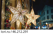 City streets advent Christmas decorations by night. Festive Xmas decor, colorful ornaments in urban setting. Holiday decorations of building or shops glow brightly, shiny stars. Illuminated ornaments. Стоковое AI-видео, аниматор Марина Демидюк / Фотобанк Лори