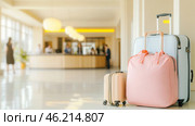 Travel bags in modern hotel lobby with blurred receptionists. Стоковое AI-изображение, AI-художник Анастасия Золотницкая / Фотобанк Лори