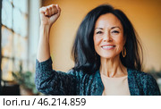 Middle aged hispanic woman with raised fist of empowerment, strength and women solidarity, International Womens Day concept. Стоковое AI-изображение, AI-художник Анастасия Золотницкая / Фотобанк Лори