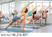 Girl stretching in Utthita Parsvakonasana asana at group yoga class. Стоковое фото, фотограф Яков Филимонов / Фотобанк Лори