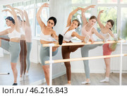 Slender young girls doing leg stretching holding by ballet barre. Стоковое фото, фотограф Яков Филимонов / Фотобанк Лори