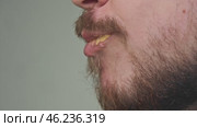 The man greedily takes a big bite of a greasy hamburger, which is drenched in sauce. Junk food. Стоковое видео, видеограф Strunov David / Фотобанк Лори