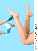 Beautiful young woman and hands epilating her legs with modern photoepilator on blue background. Стоковое фото, фотограф Pixel_shot / Фотобанк Лори