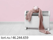 Electric convector heater, piggy bank and scarf near pink wall. Heating season. Стоковое фото, фотограф Pixel_shot / Фотобанк Лори